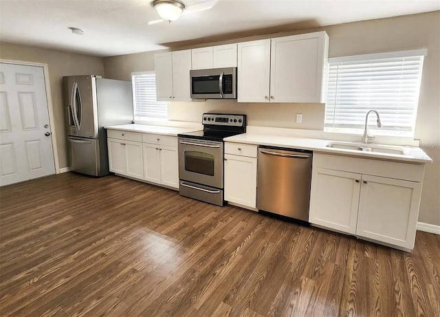 kitchen with dark wood-type flooring, appliances with stainless steel finishes, white cabinetry, and a healthy amount of sunlight