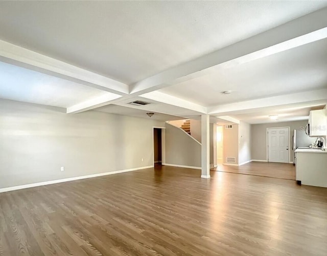 unfurnished living room featuring hardwood / wood-style flooring, beamed ceiling, and sink