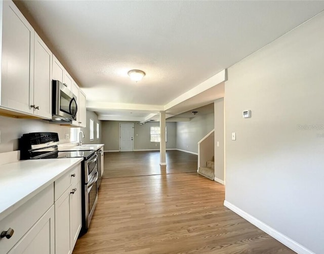 kitchen featuring light hardwood / wood-style flooring, sink, white cabinetry, appliances with stainless steel finishes, and a textured ceiling