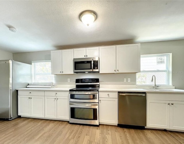 kitchen with white cabinetry, stainless steel appliances, light hardwood / wood-style flooring, and sink