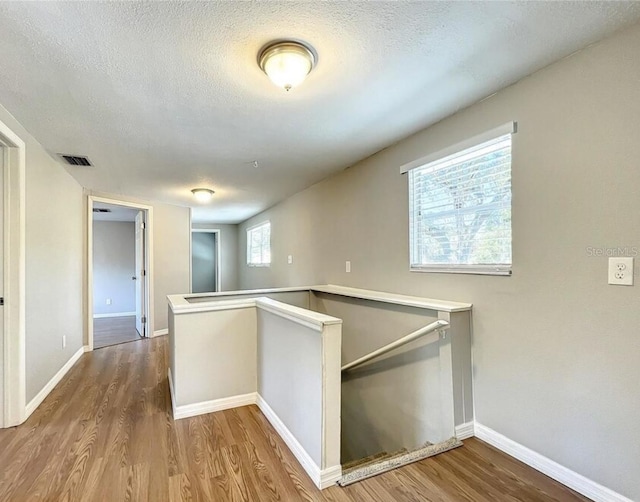 corridor featuring a textured ceiling and hardwood / wood-style flooring