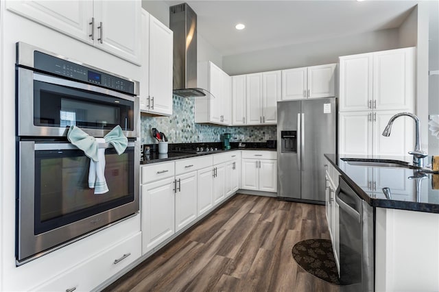 kitchen with dark hardwood / wood-style floors, stainless steel appliances, white cabinets, wall chimney exhaust hood, and sink