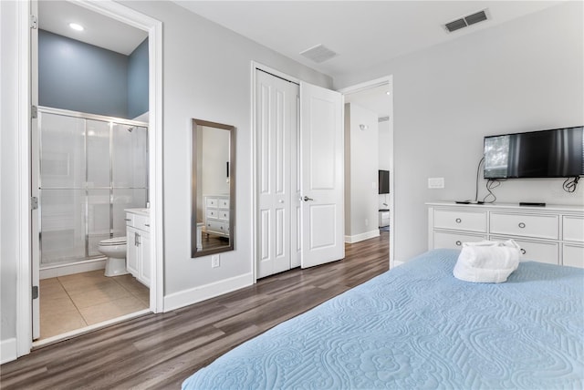 bedroom with hardwood / wood-style flooring, a closet, and ensuite bathroom