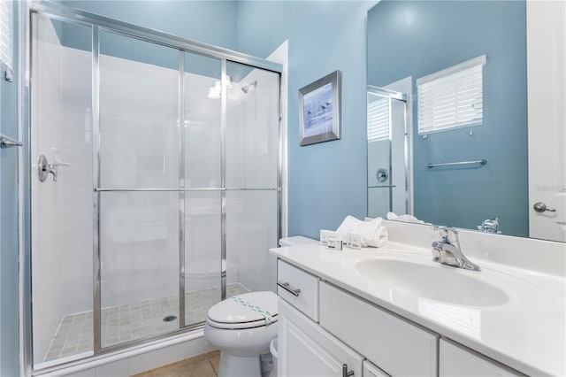 bathroom featuring vanity, toilet, a shower with door, and tile patterned floors