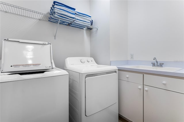 clothes washing area with independent washer and dryer, sink, and cabinets