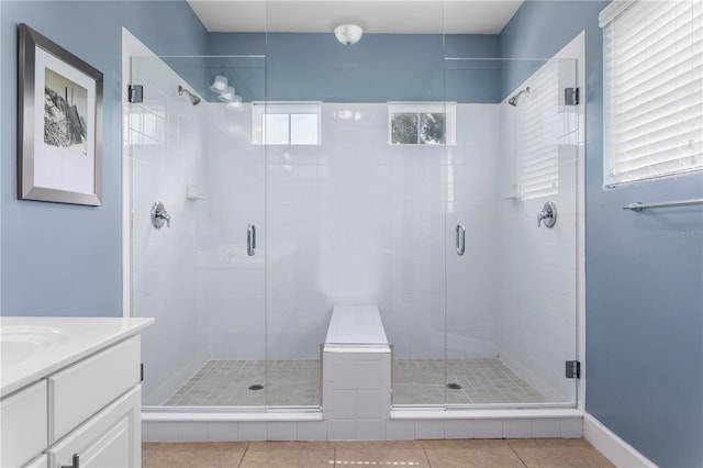 bathroom with tile patterned flooring, walk in shower, vanity, and plenty of natural light