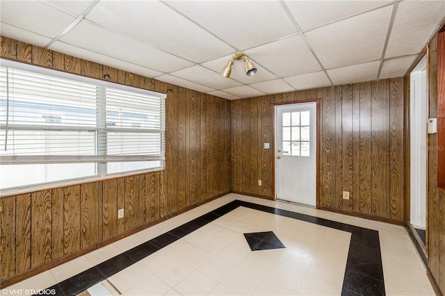 spare room featuring a drop ceiling and wood walls