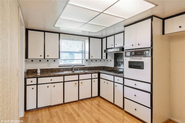 kitchen featuring white oven, light hardwood / wood-style flooring, sink, and white cabinetry