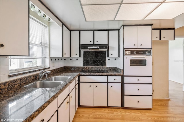 kitchen with sink, white cabinetry, white oven, and light hardwood / wood-style floors