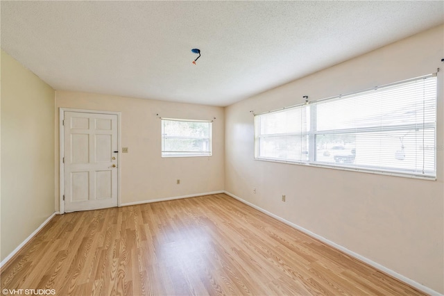 spare room with light hardwood / wood-style floors and a textured ceiling