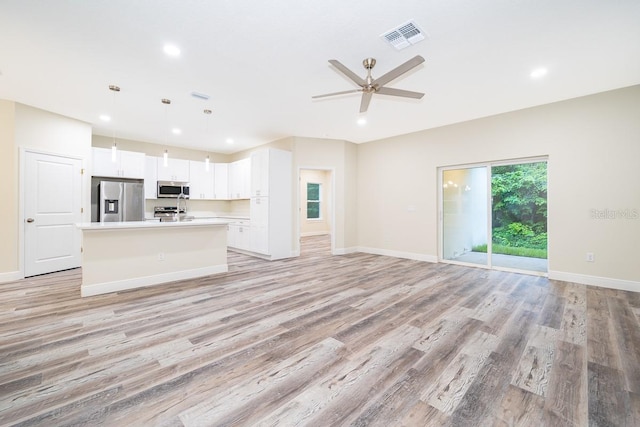 unfurnished living room with light wood-type flooring and ceiling fan