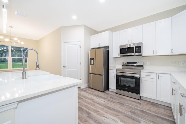 kitchen with an inviting chandelier, appliances with stainless steel finishes, light hardwood / wood-style flooring, and white cabinetry