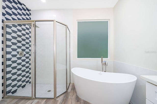 bathroom with independent shower and bath, vanity, and hardwood / wood-style floors