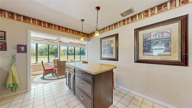 kitchen featuring a kitchen island, dark brown cabinets, hanging light fixtures, and light tile patterned floors