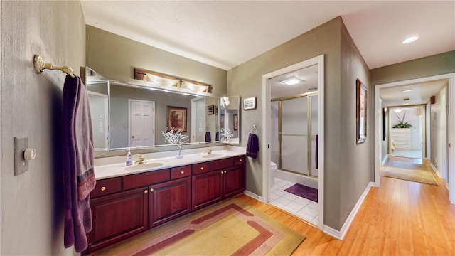 bathroom featuring vanity, toilet, a shower with shower door, and hardwood / wood-style floors