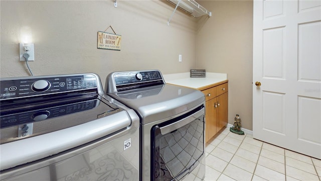 washroom with washer and dryer, cabinets, and light tile patterned floors