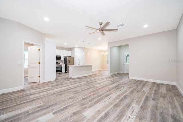 unfurnished living room featuring ceiling fan, sink, and light hardwood / wood-style flooring