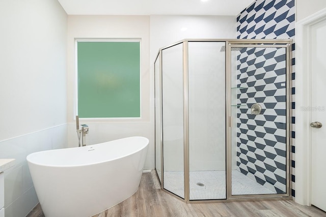 bathroom with hardwood / wood-style flooring, tile walls, and separate shower and tub