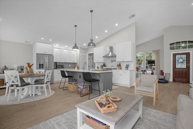 living room with high vaulted ceiling, light wood-type flooring, and sink