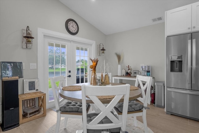 dining space featuring vaulted ceiling, light tile patterned floors, and french doors