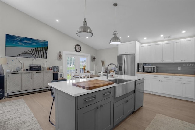 kitchen featuring appliances with stainless steel finishes, gray cabinetry, white cabinets, light wood-type flooring, and sink