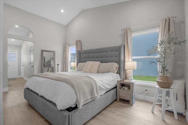 bedroom featuring multiple windows, light hardwood / wood-style flooring, and high vaulted ceiling