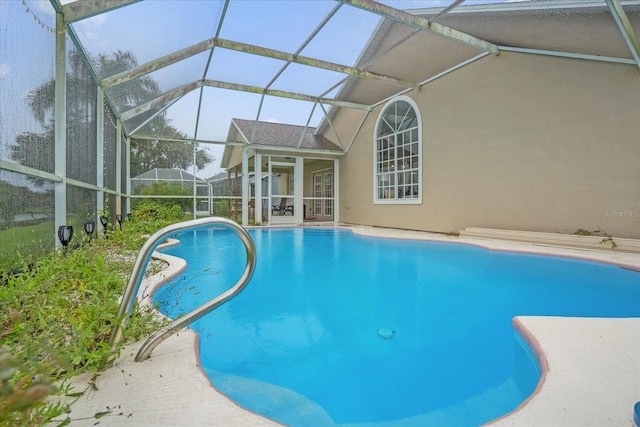 view of pool with glass enclosure and a patio