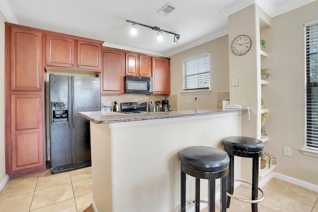 kitchen with kitchen peninsula, black appliances, light tile patterned floors, crown molding, and light stone countertops