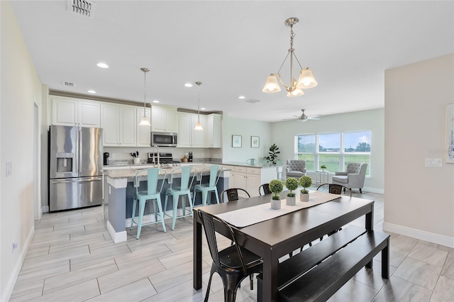 dining space featuring ceiling fan with notable chandelier and light hardwood / wood-style floors