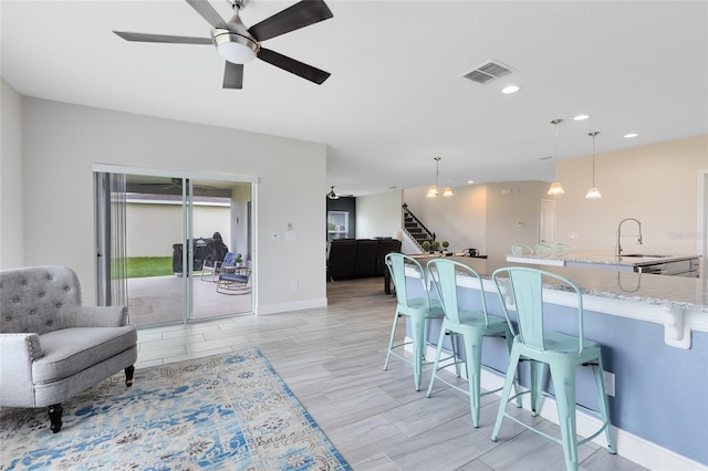 dining space featuring ceiling fan with notable chandelier, light wood-type flooring, and sink