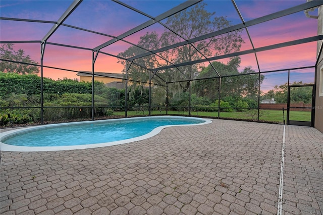 pool at dusk with a patio area and glass enclosure