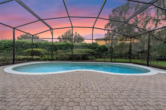 pool at dusk with a patio and glass enclosure