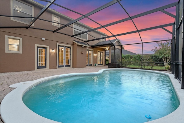 pool at dusk with a patio area and a lanai