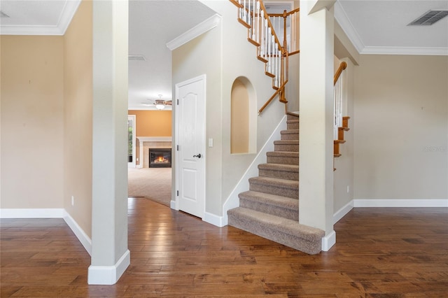 stairway with crown molding, hardwood / wood-style flooring, and ceiling fan