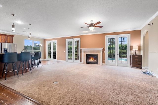 living room with french doors, a textured ceiling, a healthy amount of sunlight, and crown molding