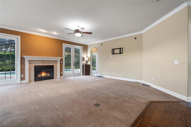 unfurnished living room featuring crown molding, a textured ceiling, a wealth of natural light, and carpet floors