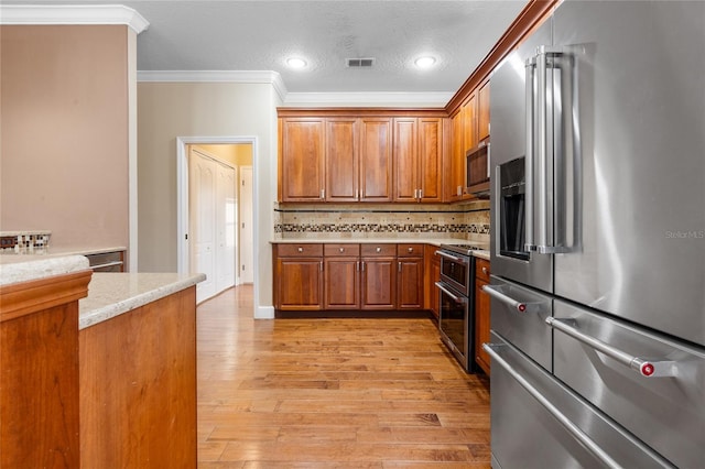 kitchen featuring tasteful backsplash, light stone countertops, light hardwood / wood-style floors, stainless steel appliances, and crown molding