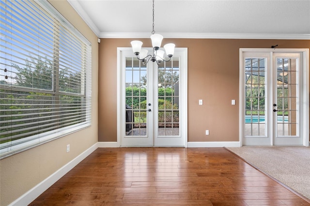 unfurnished dining area with ornamental molding, french doors, hardwood / wood-style floors, and a notable chandelier