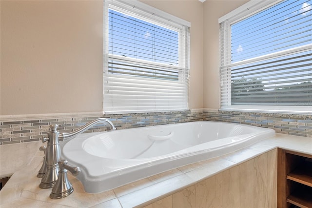 bathroom featuring a relaxing tiled tub and plenty of natural light