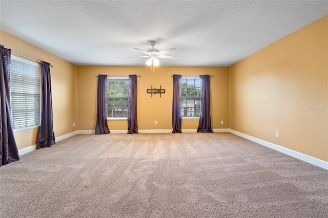 spare room with a textured ceiling, light colored carpet, and ceiling fan