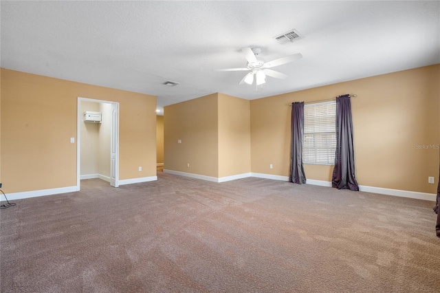 spare room featuring an AC wall unit, carpet, and ceiling fan