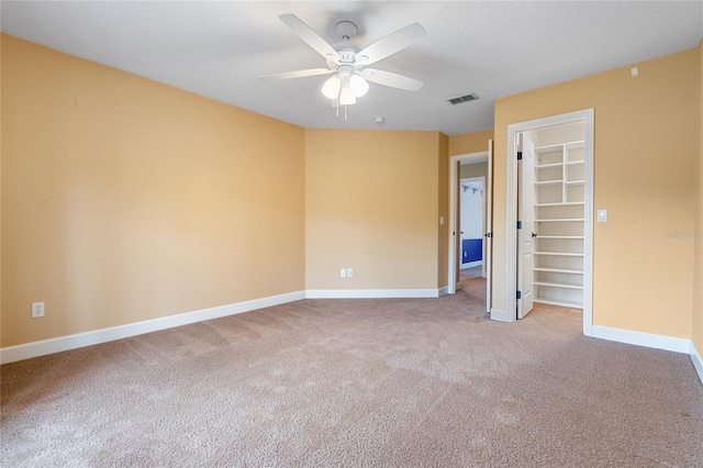 unfurnished bedroom with a spacious closet, carpet floors, a closet, and ceiling fan