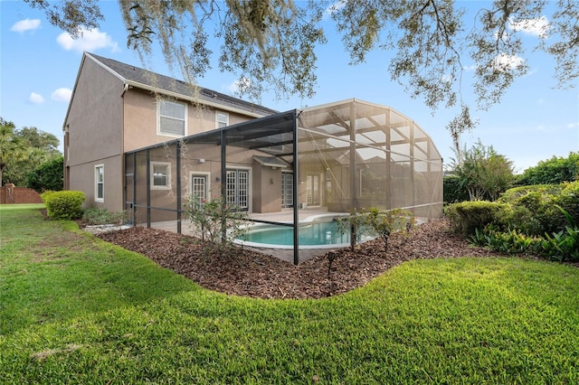 rear view of property featuring a patio area, a lawn, and glass enclosure