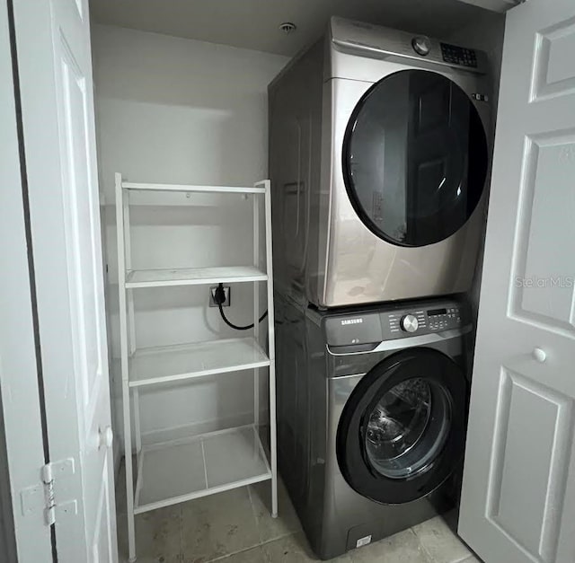 laundry area with light tile patterned flooring and stacked washing maching and dryer