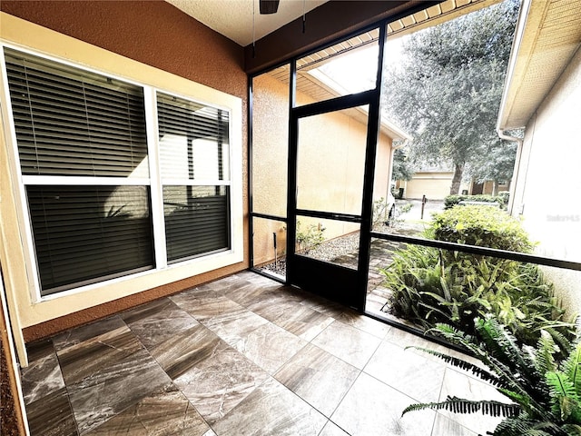 unfurnished sunroom with ceiling fan and a healthy amount of sunlight