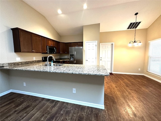 kitchen with dark brown cabinets, vaulted ceiling, light stone counters, kitchen peninsula, and appliances with stainless steel finishes