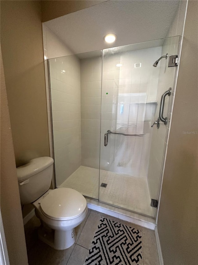 bathroom featuring tile patterned floors, a shower with shower door, a textured ceiling, and toilet