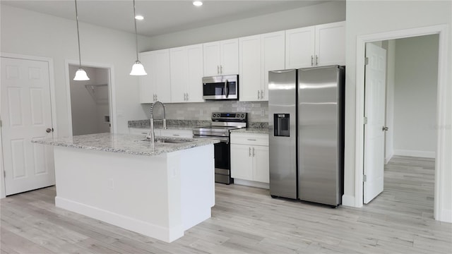 kitchen featuring a kitchen island with sink, hanging light fixtures, stainless steel appliances, and white cabinets