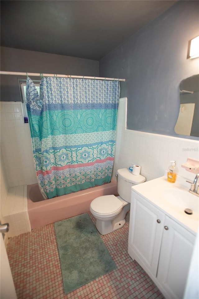 full bathroom featuring toilet, shower / tub combo with curtain, vanity, and tile walls