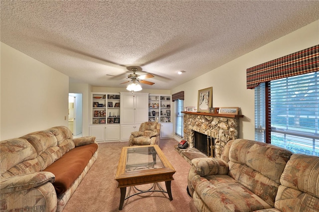 carpeted living room featuring ceiling fan, a stone fireplace, and a textured ceiling